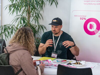 Ein Mann vom Verein Neustart berät eine interessierte Besucherin