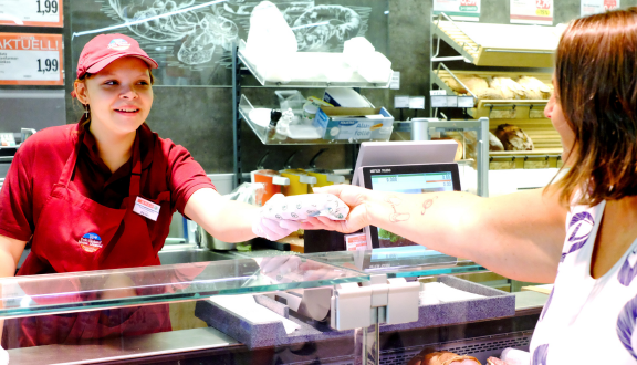 eine junge bedient hinter der Feinkosttheke in einem Spar-Markt