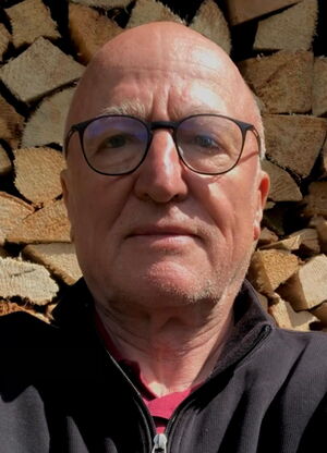 Auf dem Foto sieht man Joe Weidenholzer vor einem Holzstapel