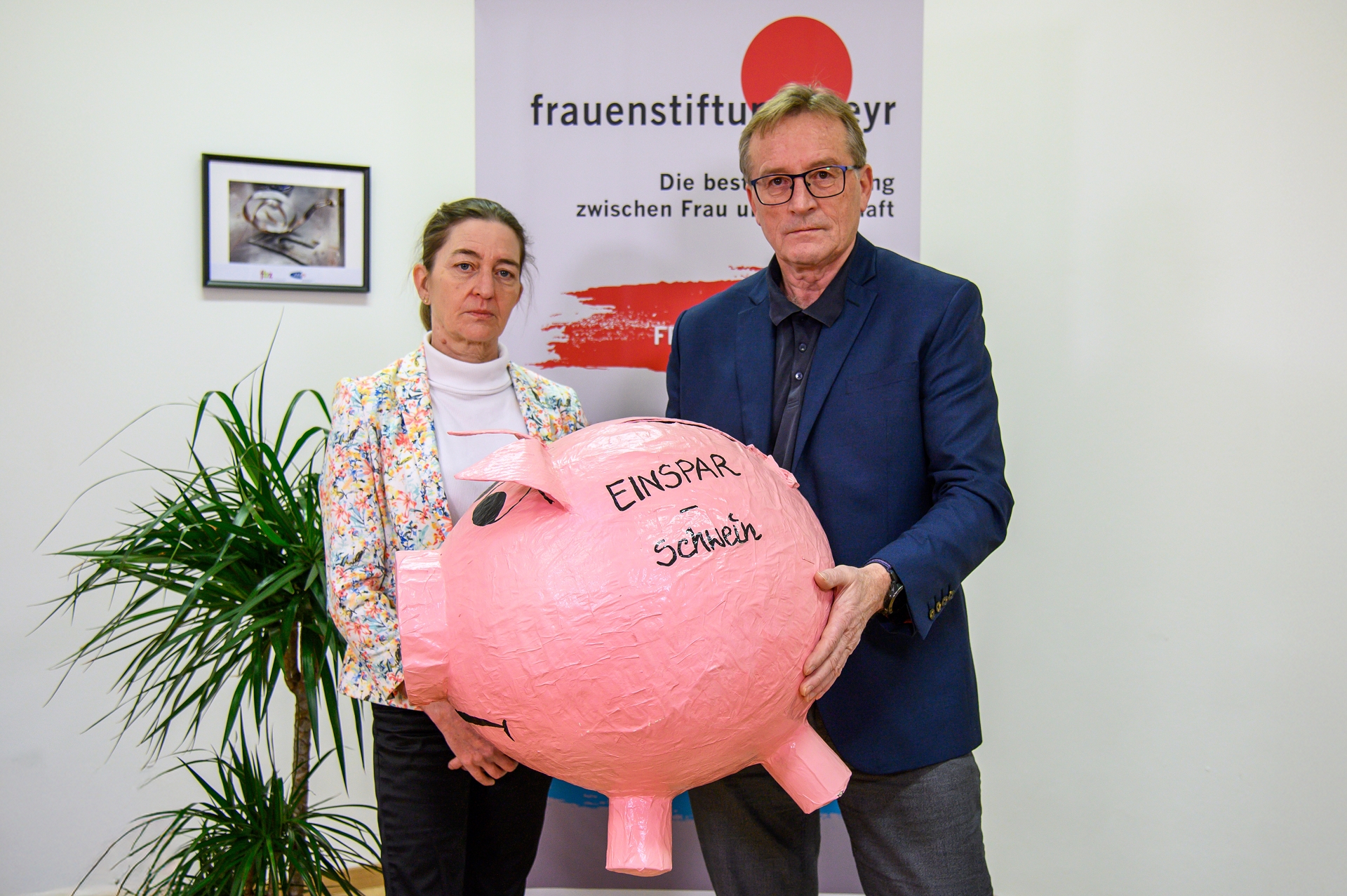 Klaudia Burtscher und Josef Pürmayr halten das Einsparschwein, eine übergroßes Sparschwein